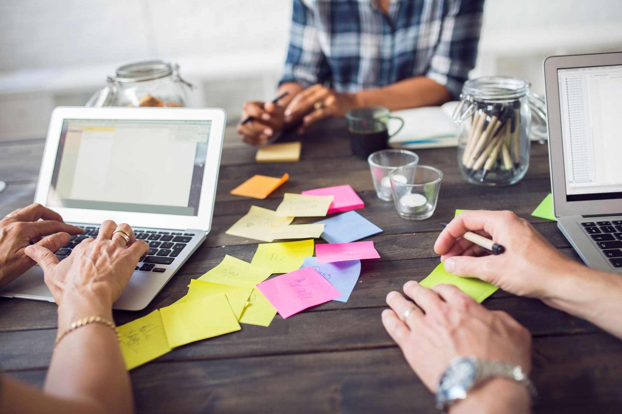 Tres compañeros de trabajo usando el ordenador y post-its para organizarse