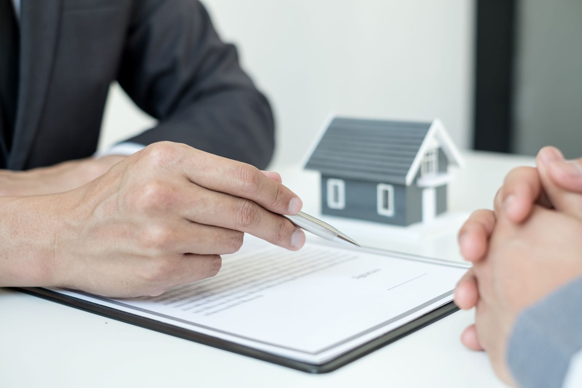 Agente inmobiliario hablando con un cliente y con un contrato para firmar delante.